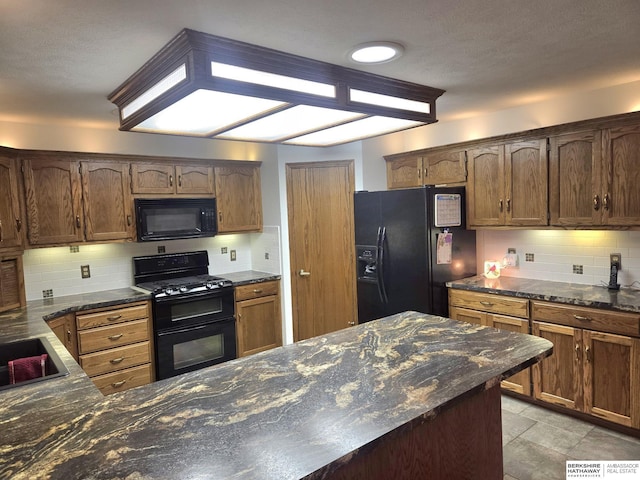 2205 Hidden Canyon Rd, Plattsmouth, NE 68048 - kitchen with black appliances, backsplash, dark stone countertops, a peninsula, and a sink