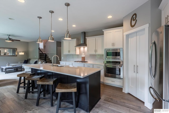 2203 N 188th Ave, Elkhorn, NE 68022 - kitchen featuring stainless steel appliances, a sink, wall chimney range hood, a ceiling fan, and decorative backsplash