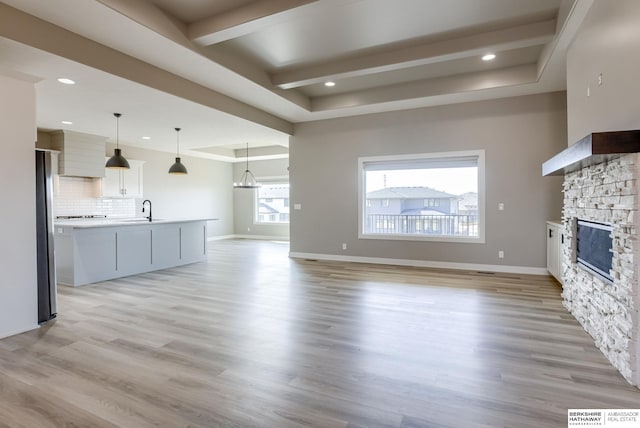 3938 S 207th St, Elkhorn, NE 68022 - unfurnished living room with a sink, a fireplace, light wood-type flooring, baseboards, and beam ceiling