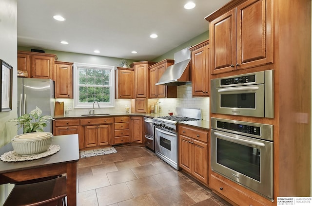 5119 Hamilton St, Omaha, NE 68132 - kitchen with stainless steel appliances, wall chimney exhaust hood, a sink, brown cabinets, and recessed lighting