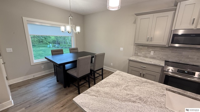 12667 161st Ave, Bennington, NE 68007 - dining space with a chandelier, wood finished floors, and baseboards