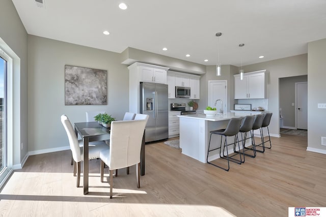 350 N 105th St, Lincoln, NE 68527 - kitchen featuring stainless steel appliances, light wood-style floors, a sink, a breakfast bar, and an island with sink