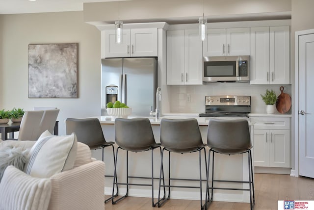 350 N 105th St, Lincoln, NE 68527 - kitchen featuring appliances with stainless steel finishes, decorative backsplash, a breakfast bar area, light wood-style flooring, and light countertops