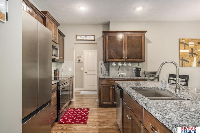 10202 N 152nd Ave, Bennington, NE 68007 - kitchen featuring a sink, stainless steel appliances, wood finished floors, decorative backsplash, and light stone countertops