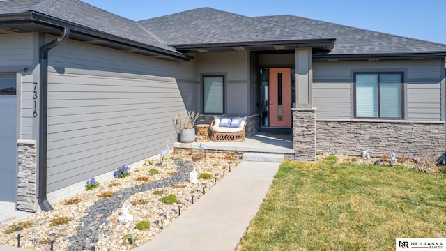 7316 Gerald Ave, Lincoln, NE 68516 - doorway to property with a garage, stone siding, roof with shingles, and a lawn