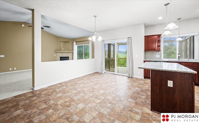 6713 N 148th St, Omaha, NE 68116 - kitchen with open floor plan, a fireplace, a kitchen island, light stone finish flooring, and lofted ceiling