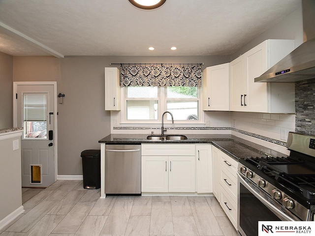 2000 N 53rd St, Lincoln, NE 68504 - kitchen featuring stainless steel appliances, wall chimney range hood, dark stone countertops, white cabinetry, and decorative backsplash