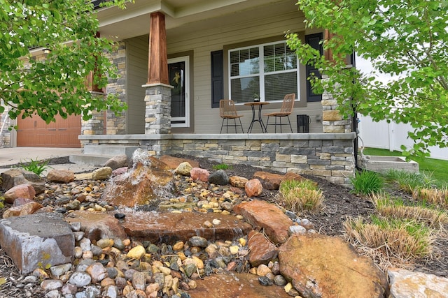 18337 Polk St, Omaha, NE 68135 - doorway to property with covered porch, a garage, driveway, and stone siding