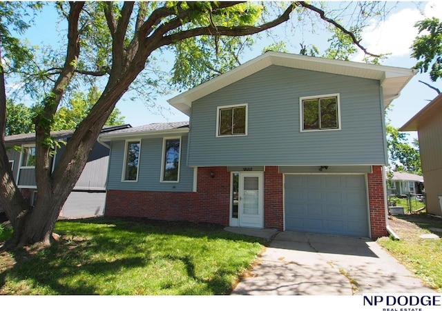 5807 S 136th St, Omaha, NE 68137 - split level home with brick siding, an attached garage, a front yard, and concrete driveway