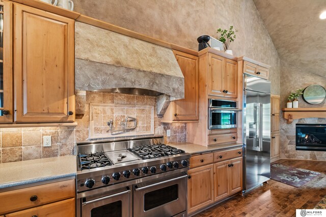 4725 S 184th Plz, Omaha, NE 68135 - kitchen featuring high quality appliances, custom exhaust hood, decorative backsplash, a tiled fireplace, and dark wood-style flooring