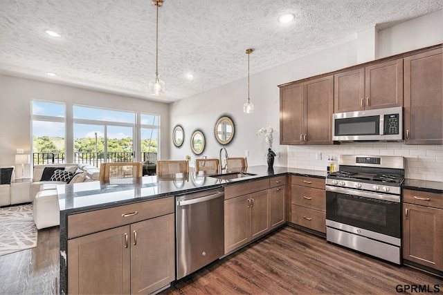 630 N 46th St, Omaha, NE 68132 - kitchen with stainless steel appliances, a sink, a peninsula, a textured ceiling, and dark wood finished floors