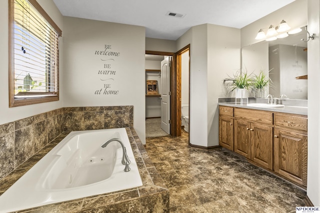 19677 Lamont St, Omaha, NE 68130 - full bathroom featuring vanity, a tub with jets, toilet, baseboards, and stone finish floors
