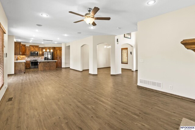 19677 Lamont St, Omaha, NE 68130 - unfurnished living room with a ceiling fan, recessed lighting, dark wood-type flooring, arched walkways, and a sink
