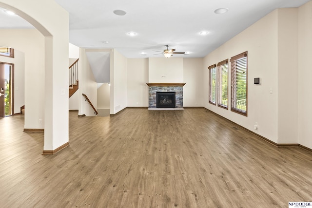 19677 Lamont St, Omaha, NE 68130 - unfurnished living room featuring ceiling fan, wood finished floors, a fireplace, baseboards, and arched walkways
