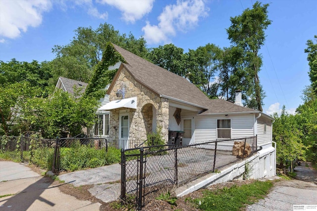 712 Bancroft St, Omaha, NE 68108 - tudor-style house with stone siding, a chimney, roof with shingles, and a garage