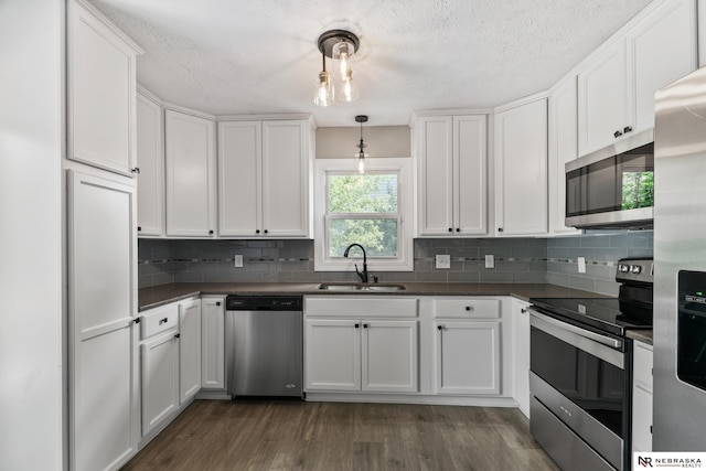 2000 Murray Rd, Plattsmouth, NE 68048 - kitchen with stainless steel appliances, a sink, dark countertops, white cabinetry, and a textured ceiling