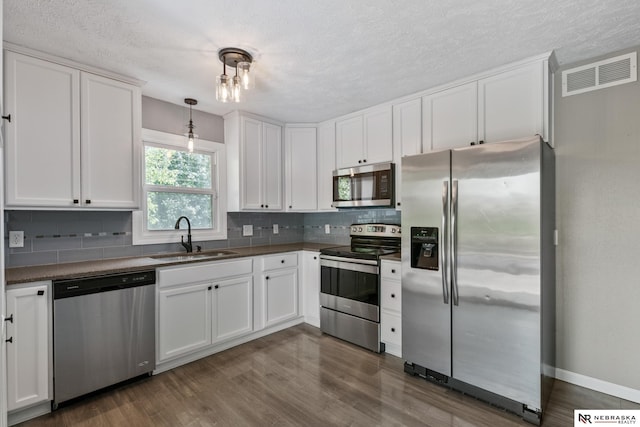 2000 Murray Rd, Plattsmouth, NE 68048 - kitchen featuring stainless steel appliances, a sink, dark countertops, backsplash, and white cabinets