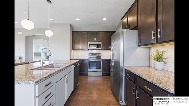 20904 Camden Ave, Omaha, NE 68022 - kitchen featuring appliances with stainless steel finishes, a sink, dark brown cabinets, light stone countertops, and pendant lighting