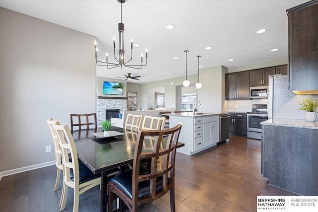 20904 Camden Ave, Omaha, NE 68022 - dining area with recessed lighting, a chandelier, a stone fireplace, dark wood-style flooring, and ceiling fan