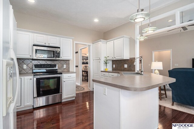 7409 N 160th St, Bennington, NE 68007 - kitchen featuring appliances with stainless steel finishes, a sink, a peninsula, dark wood-type flooring, and backsplash