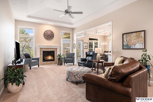 7409 N 160th St, Bennington, NE 68007 - living area with carpet floors, a tiled fireplace, a tray ceiling, a ceiling fan, and baseboards