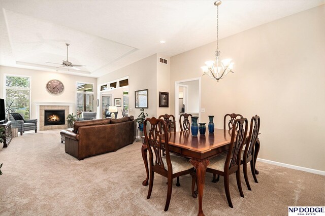 7409 N 160th St, Bennington, NE 68007 - dining room with light carpet, a chandelier, a tray ceiling, a ceiling fan, and a tile fireplace