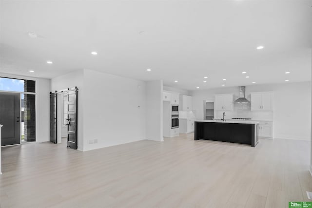 5409 N 196th Ave, Elkhorn, NE 68022 - unfurnished living room with a barn door, a sink, light wood-style flooring, recessed lighting, and baseboards