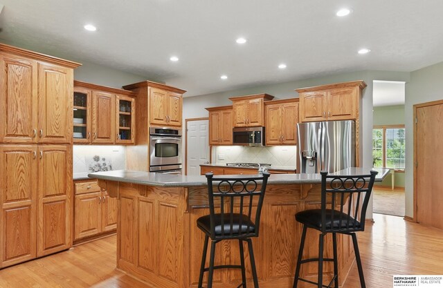 17616 Englewood St, Omaha, NE 68135 - kitchen with appliances with stainless steel finishes, light wood-type flooring, a center island with sink, a breakfast bar, and recessed lighting