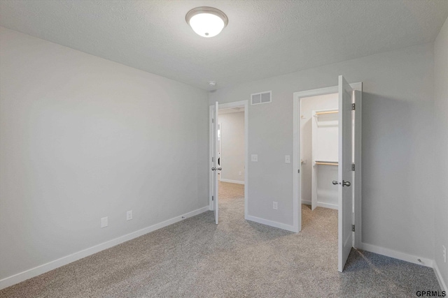 17312 Potter St, Bennington, NE 68005 - unfurnished bedroom with a walk in closet, carpet floors, baseboards, a closet, and a textured ceiling