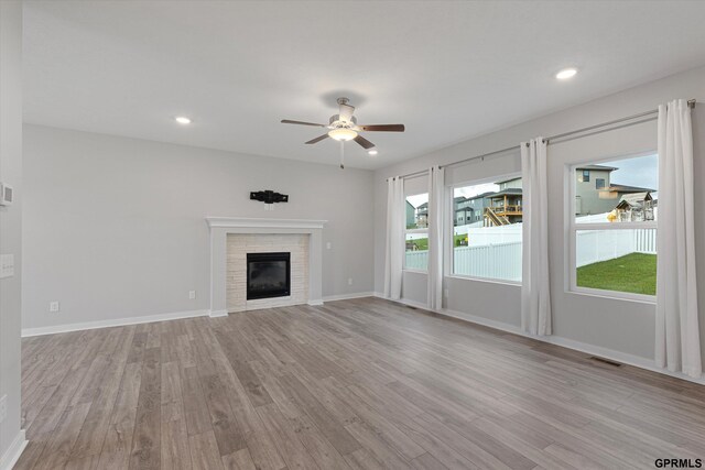 17312 Potter St, Bennington, NE 68005 - unfurnished living room with light wood finished floors, a ceiling fan, a glass covered fireplace, baseboards, and recessed lighting