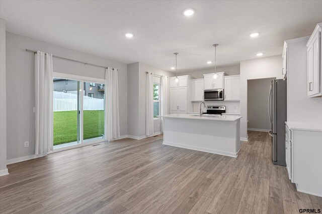 17312 Potter St, Bennington, NE 68005 - kitchen featuring stainless steel appliances, light countertops, light wood-style floors, a center island with sink, and white cabinets