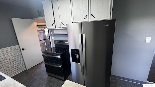 5218 Boyd St, Omaha, NE 68104 - kitchen with appliances with stainless steel finishes, white cabinetry, dark tile patterned flooring, and light countertops