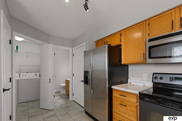 3003 Sheridan Rd, Bellevue, NE 68123 - kitchen featuring stainless steel appliances, washer and clothes dryer, light countertops, light tile patterned floors, and brown cabinetry
