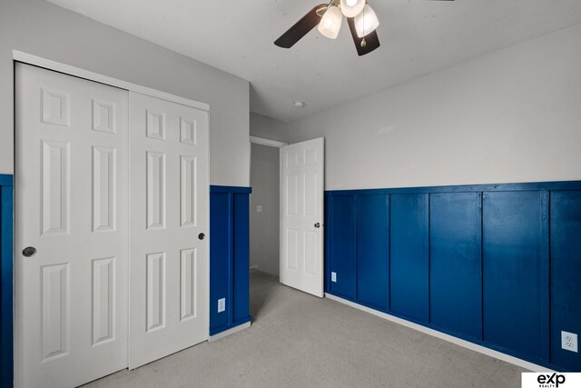 3003 Sheridan Rd, Bellevue, NE 68123 - unfurnished bedroom with wainscoting, light carpet, a closet, a ceiling fan, and a decorative wall