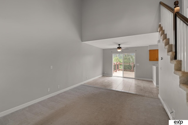 3003 Sheridan Rd, Bellevue, NE 68123 - spare room with light colored carpet, a ceiling fan, stairs, baseboards, and a towering ceiling