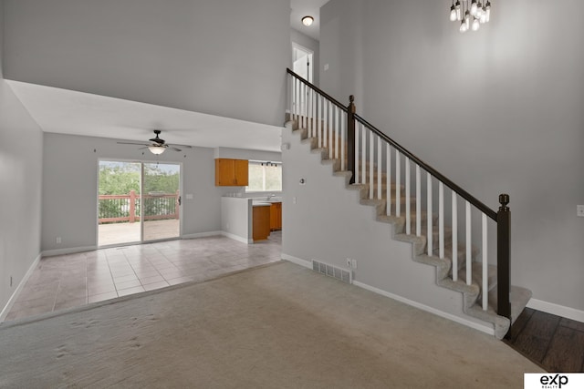 3003 Sheridan Rd, Bellevue, NE 68123 - unfurnished living room with a ceiling fan, stairway, baseboards, a towering ceiling, and light colored carpet