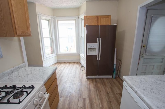 1801 Euclid Ave, Lincoln, NE 68502 - kitchen with white refrigerator with ice dispenser, light wood-style floors, brown cabinets, a textured ceiling, and light stone countertops