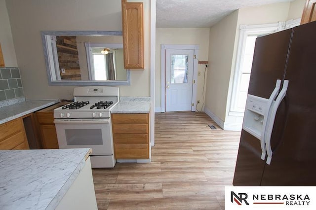 1801 Euclid Ave, Lincoln, NE 68502 - kitchen with white appliances, light wood-style flooring, light countertops, a textured ceiling, and decorative backsplash