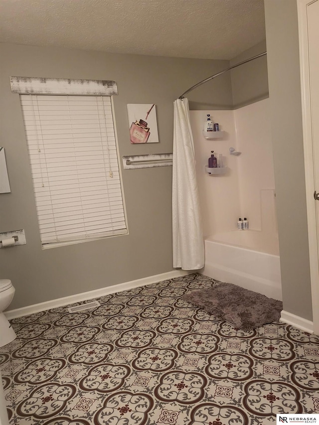 16228 Virginia St, Omaha, NE 68136 - bathroom featuring baseboards, toilet, shower / tub combo, tile patterned floors, and a textured ceiling