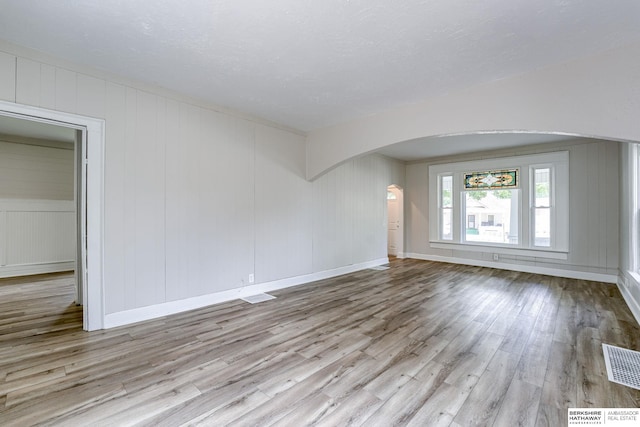 1943 Washington St, Blair, NE 68008 - unfurnished living room with arched walkways, wood finished floors, baseboards, and a decorative wall