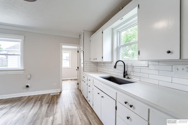 1943 Washington St, Blair, NE 68008 - kitchen with a sink, white cabinets, plenty of natural light, tasteful backsplash, and ornamental molding