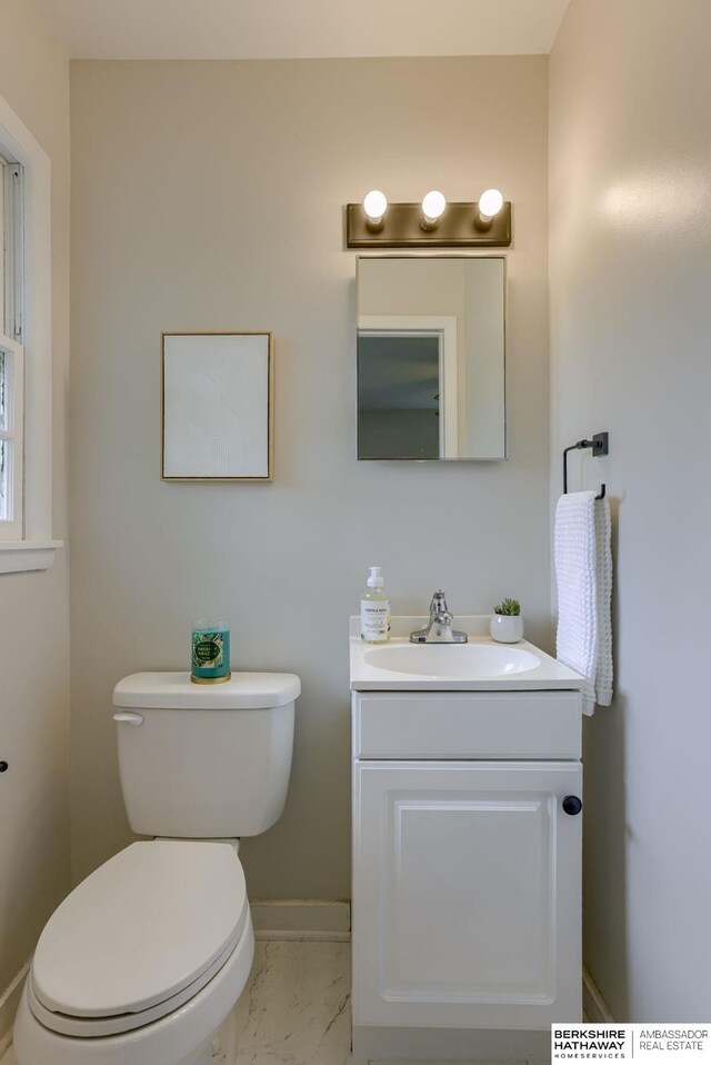 5002 S 77th Ave, Ralston, NE 68127 - bathroom featuring vanity, toilet, marble look tile flooring, and baseboards