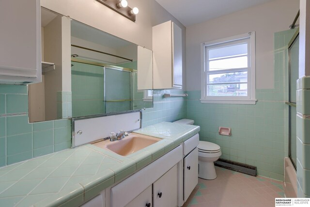 5002 S 77th Ave, Ralston, NE 68127 - full bathroom featuring tile walls, baseboard heating, vanity, toilet, and tile patterned floors