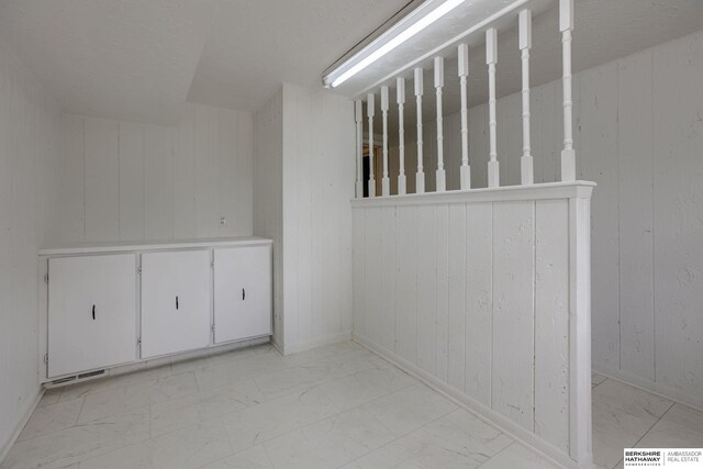 5002 S 77th Ave, Ralston, NE 68127 - additional living space with marble look tile flooring, wood walls, and baseboards