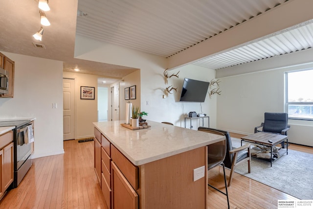 105 N 31st Ave Unit 502, Omaha, NE 68131 - kitchen featuring stainless steel appliances, a kitchen island, a kitchen bar, light wood-style flooring, and light stone countertops