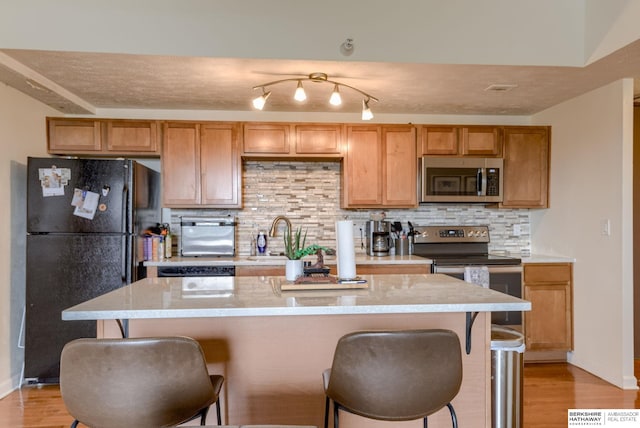 105 N 31st Ave Unit 502, Omaha, NE 68131 - kitchen with stainless steel appliances, a sink, a breakfast bar, tasteful backsplash, and light wood finished floors