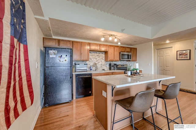 105 N 31st Ave Unit 502, Omaha, NE 68131 - kitchen with black appliances, light wood-style flooring, a kitchen island, a breakfast bar area, and decorative backsplash