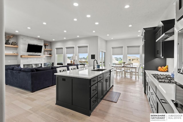 10317 S 191st Ave, Omaha, NE 68136 - kitchen with a sink, dark cabinetry, light countertops, a center island with sink, and wall chimney range hood