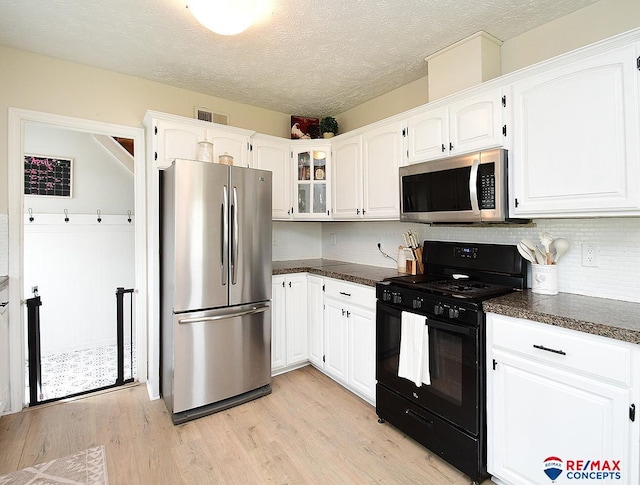 649 W 2nd St, Wahoo, NE 68066 - kitchen with appliances with stainless steel finishes, light wood-style flooring, white cabinets, glass insert cabinets, and tasteful backsplash
