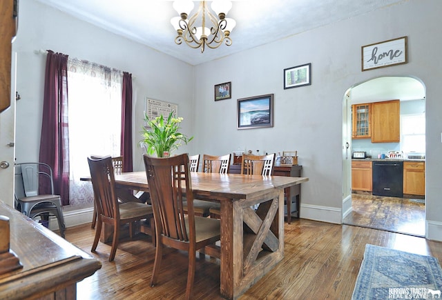 429 N 4th St, Tecumseh, NE 68450 - dining room featuring a chandelier, arched walkways, hardwood / wood-style flooring, and baseboards